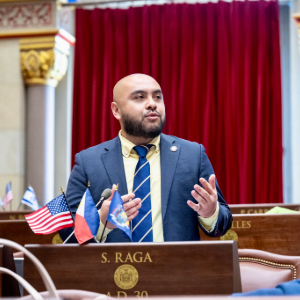 Steven Raja stands at a podium speaking with his hands.