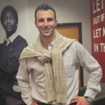 Jason Woolf standing in the Special Olympics Pennsylvania (SOPA) office in front of banner walls