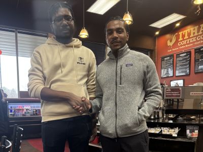 Student shakes hands with the Ithaca Coffee Co. manager while standing in the café.