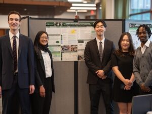 The CarbonWatch Kenya team smiles in front of their poster board.