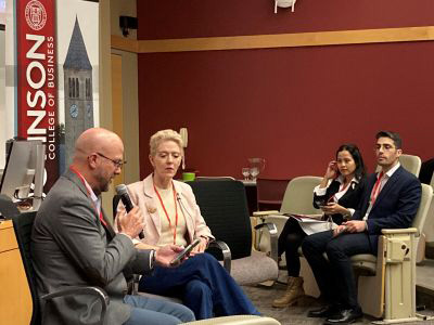 Trent Preszler asks Michelle Adelman a question; Tika Diagnestya and Daniel Madmony-Ziegler watch and listen to the fireside chat.