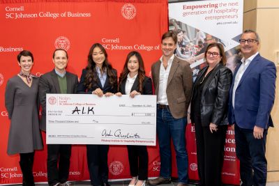 ALK members Miya Deng and Katelynn Wiseman celebrate with judges after winning first place in the 2025 Hospitality Pitch Deck Competition.