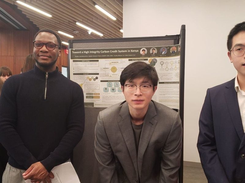 Students pose in front of their poster presentation.