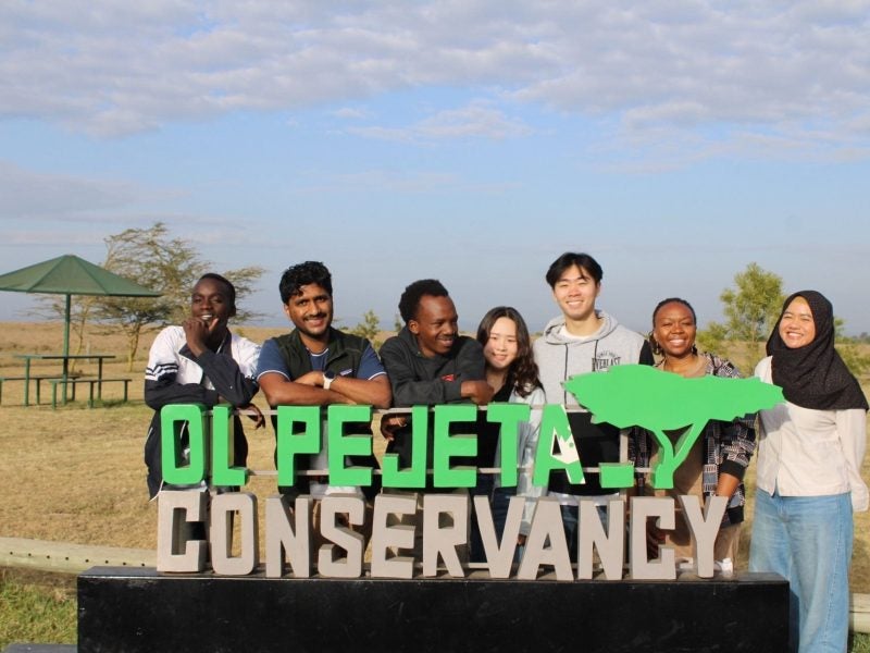 Students pose behind a conservancy sign in Kenya.