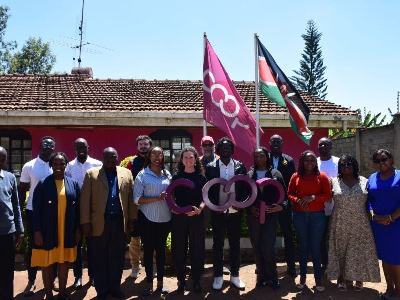 Students pose with cooperative signs and flags.