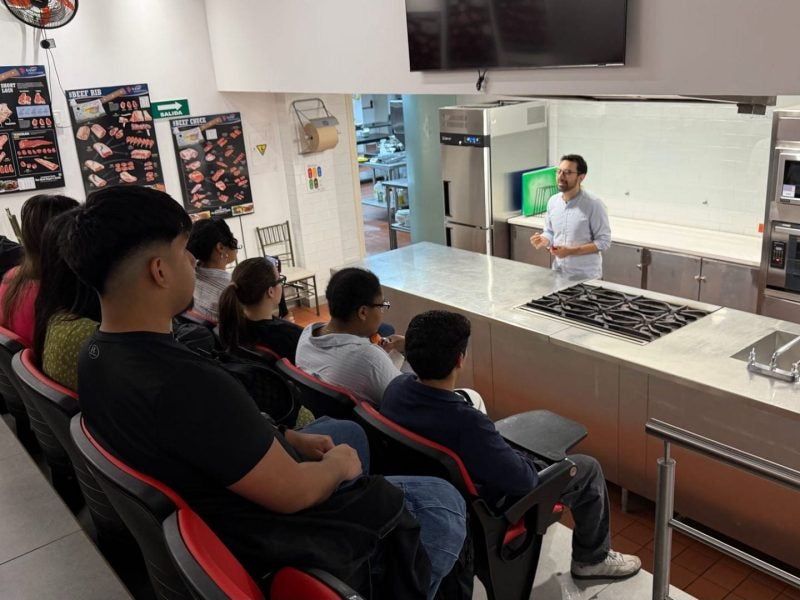 Students listen to a lecture in a test kitchen.