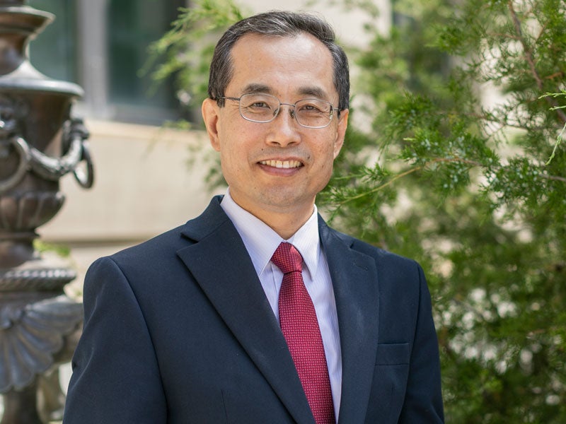 headshot Dean Zhao in front of Warren Hall