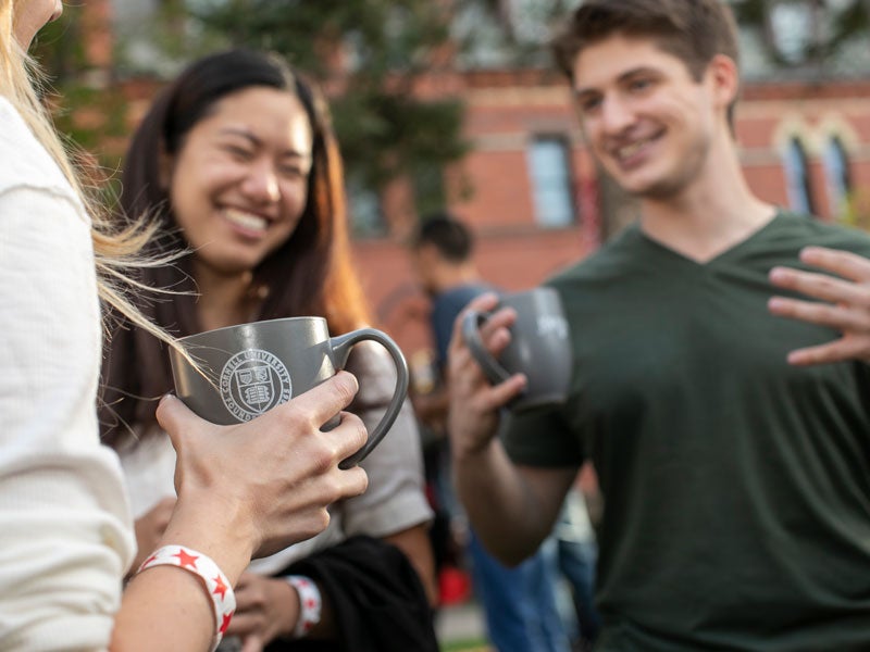 Description Students with commemorative mugs at the 2021 Johnson 75th Anniversary Kickoff Sage Social.