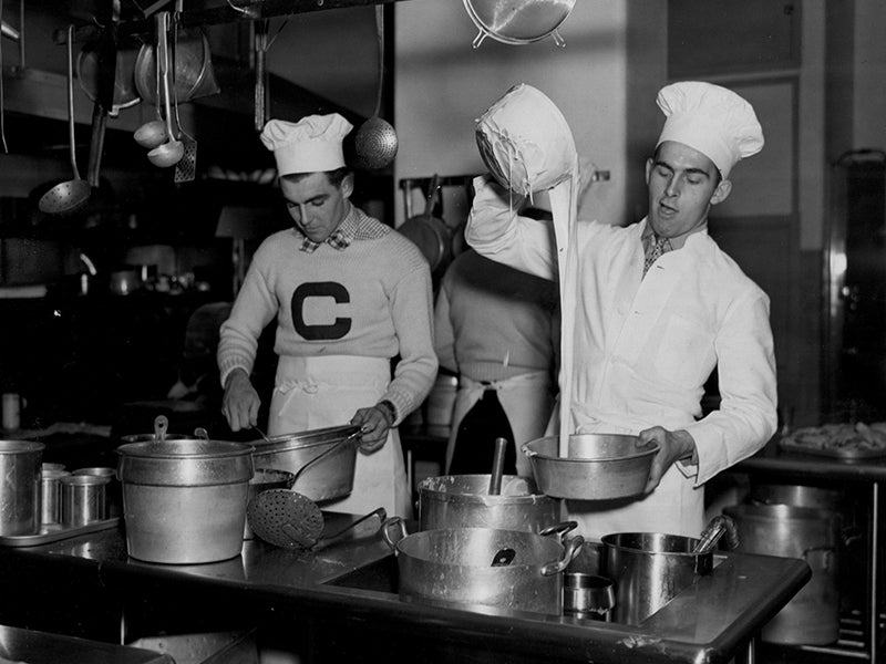 A black and white historical photo in a kitchen lab with two students baking a cake