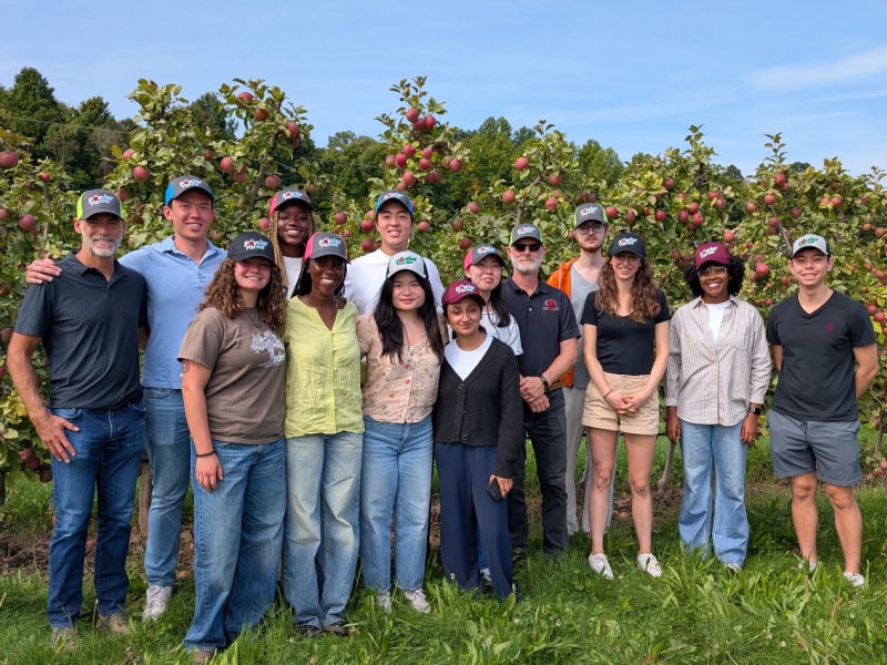 Students pose in front of apple trees at Fowler Farms. Fall 2025