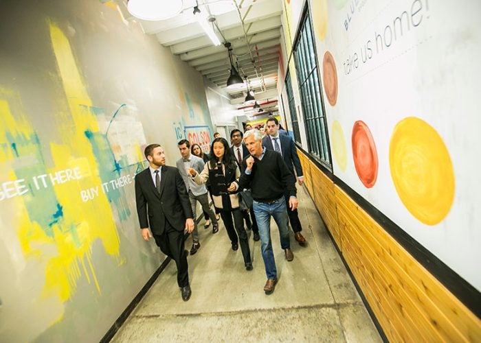 Group of people walking down hallway with quotes and imagery painted on wall