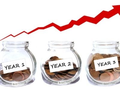 Three glass jars labeled "Year 1," "Year 2," and "Year 3" with increasing amounts of coins, and a red upward trending arrow above them