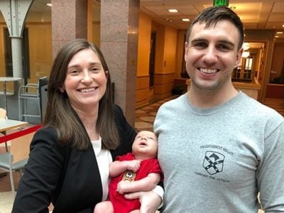 Shannon Boyle holding her child with her spouse at Sage Hall.