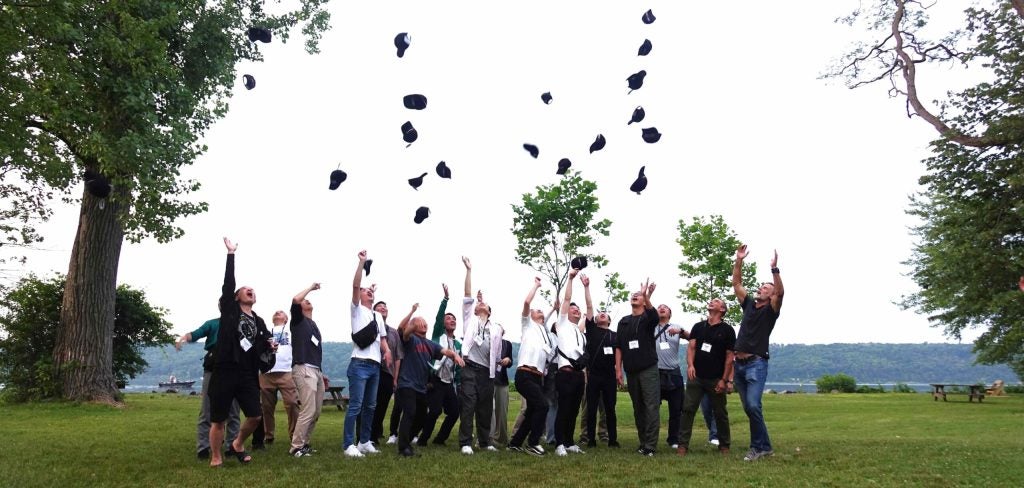 People stand outside and throw hats in the air.