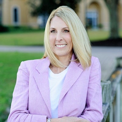 Kim Hehir &rsquo;94 wearing a lavender suit in an outdoor courtyard.