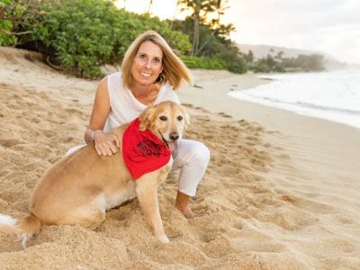 A woman on the beach with her golden retriever.