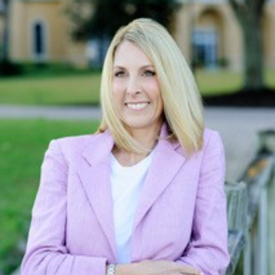 Kim Hehir &rsquo;94 wearing a lavender suit in an outdoor courtyard.