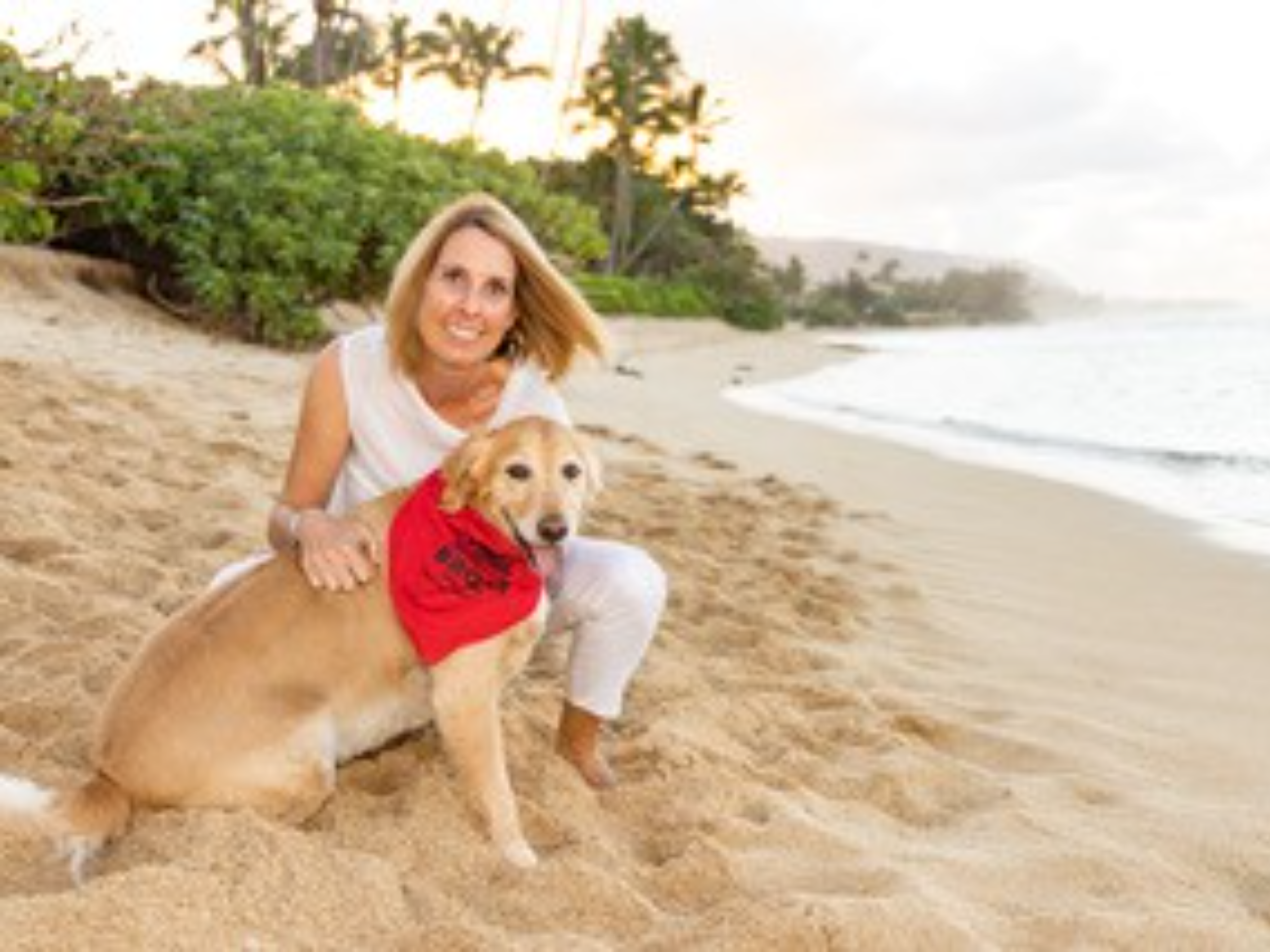 A woman on the beach with her golden retriever.
