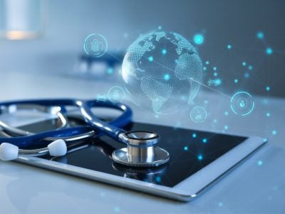 An illustration of an iPad with a stethoscope on top and a blue transparent globe over it.