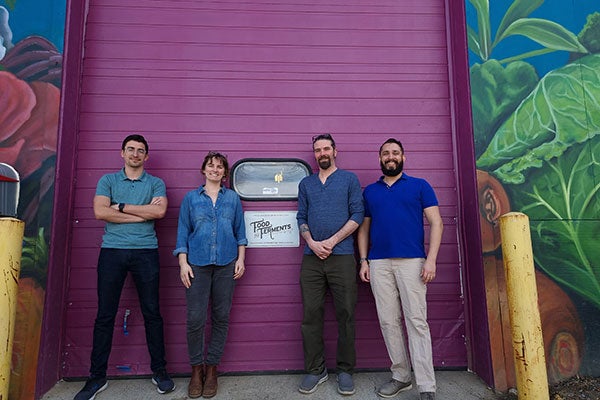 Adit Desai, Beto Dur&oacute;n, Dave Dougherty, and Carly Dougherty of Food and Ferment pose in front of a purple warehouse door.