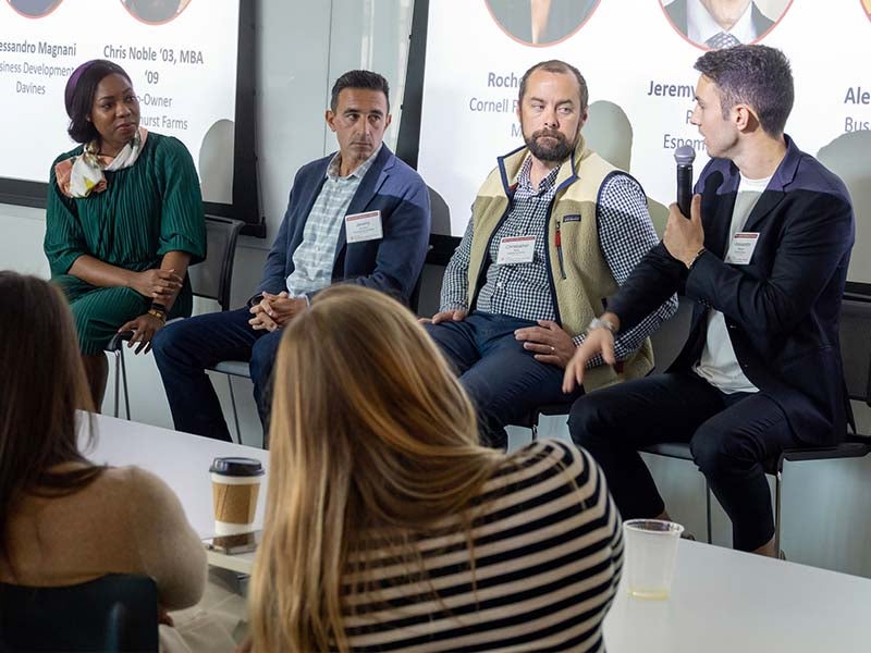 Four people sitting in front of a classroom on a panel discussion.