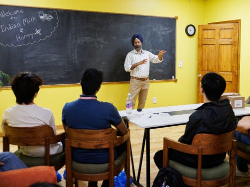 A group of students seated in a classroom listening to Amrit Singh, co-founder and operator of Indian Milk & Honey, at his family business.