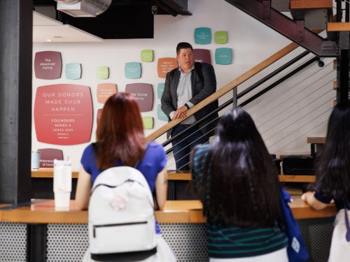 The instructor, Brad Treat, standing in front of a board with post-it notes at eHub and two female students watching.